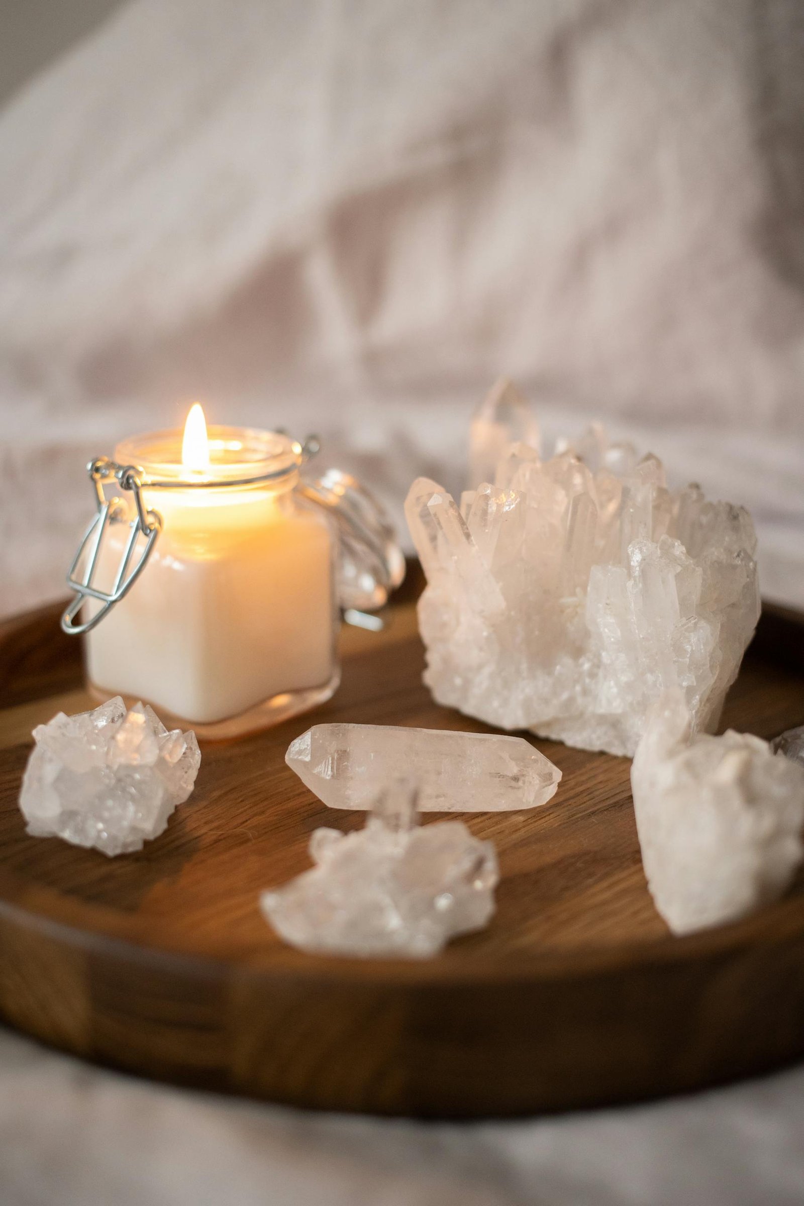 A serene still life of a lit candle surrounded by crystals on a wooden tray, perfect for relaxation.