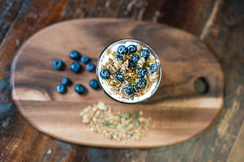 Top view of a nutritious granola parfait with fresh blueberries in a glass bowl, perfect for a healthy snack.