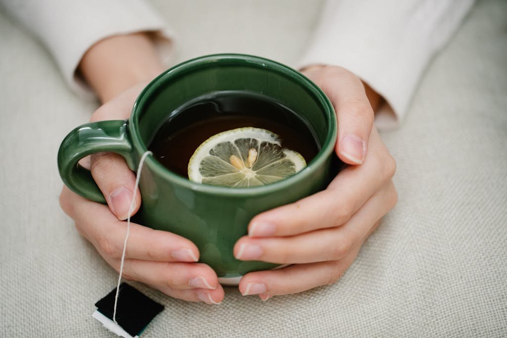 A cozy scene of a person holding a warm cup of lemon tea, providing a sense of comfort and relaxation.