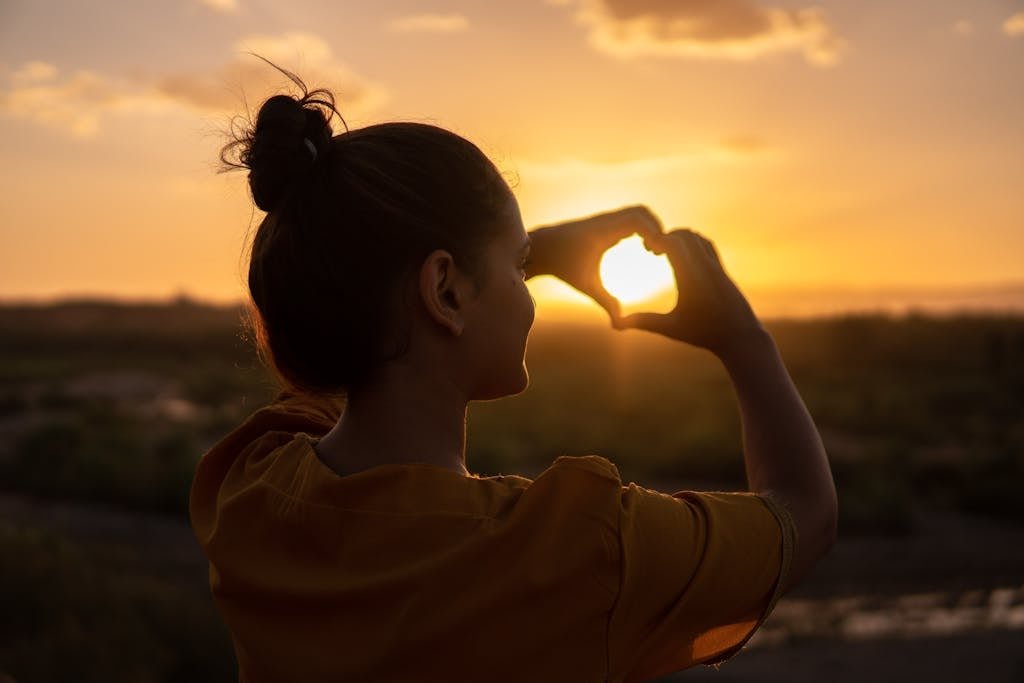 A silhouette of a young woman forming a heart shape at sunset in Kelâat M'Gouna, Morocco.
self-love habits