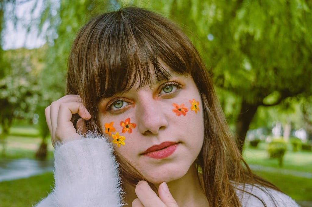 Young woman outdoors with floral face paint, showcasing beauty and style. Self-love habits