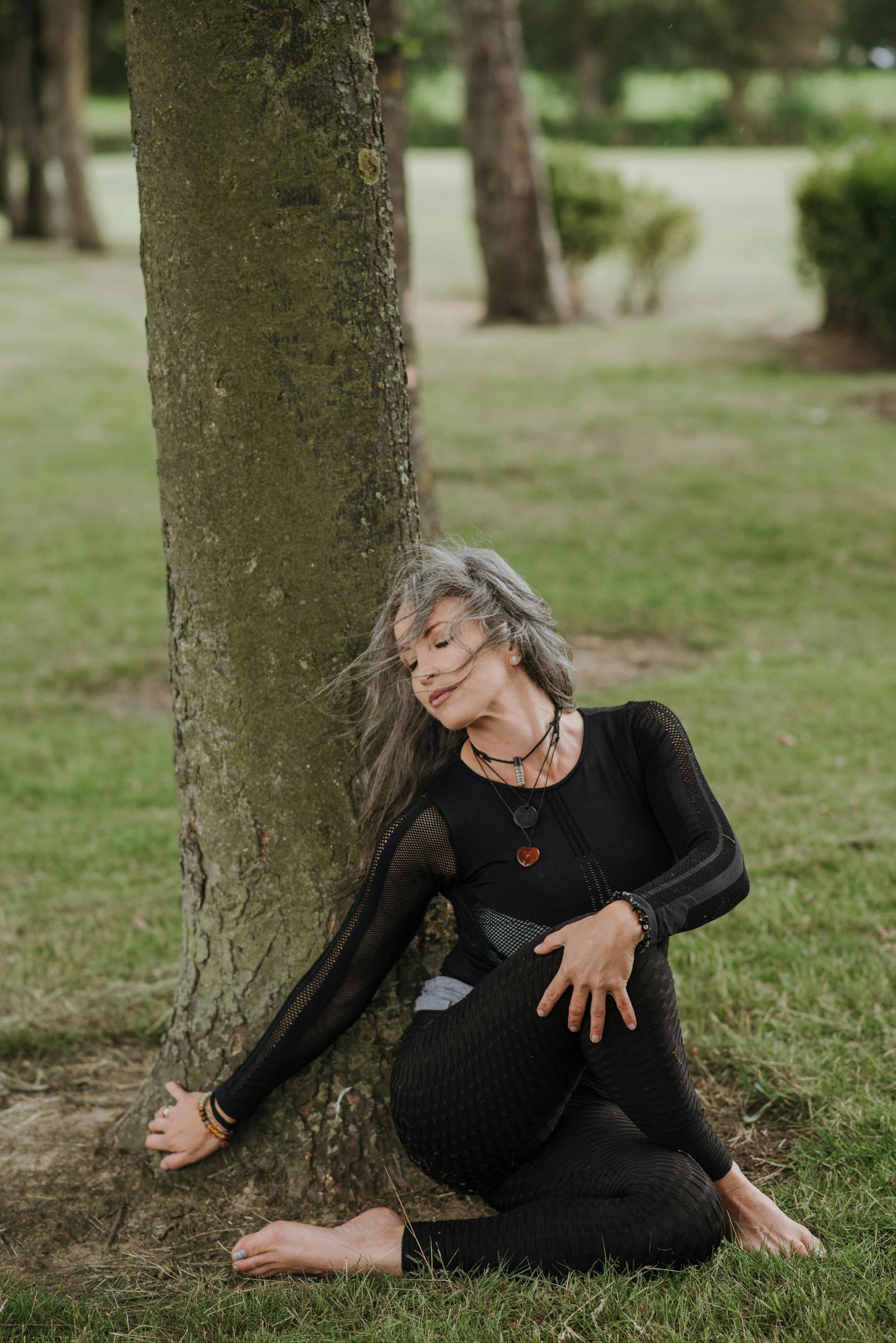 Woman practicing seated twist yoga pose in a tranquil park setting.