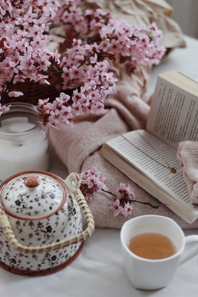 A calming setting with tea, cherry blossoms, and a book evokes comfort and relaxation.