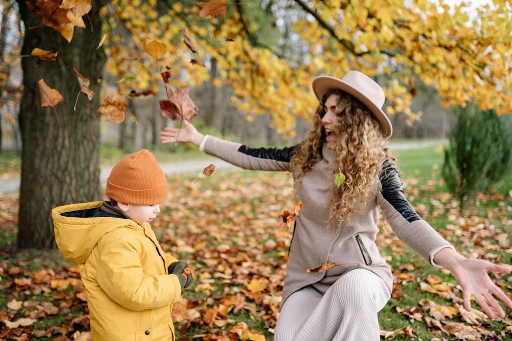 A joyful mother and child playing with autumn leaves in a park. Captured in vibrant fall colors. Outdoor Fall Bucket List Activities