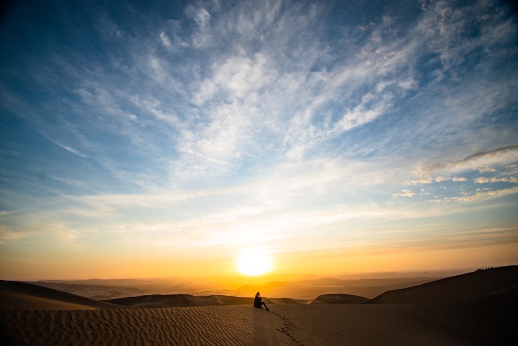 A stunning sunset over desert dunes in Paracas, Peru, with a solitary silhouette capturing tranquility. Powerful Affirmations